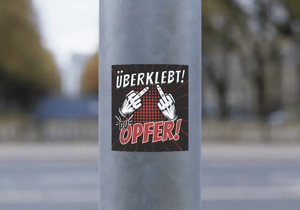Nahaufnahme des überklebt du opfer Stickers mit glänzender Oberfläche und frechem Motiv