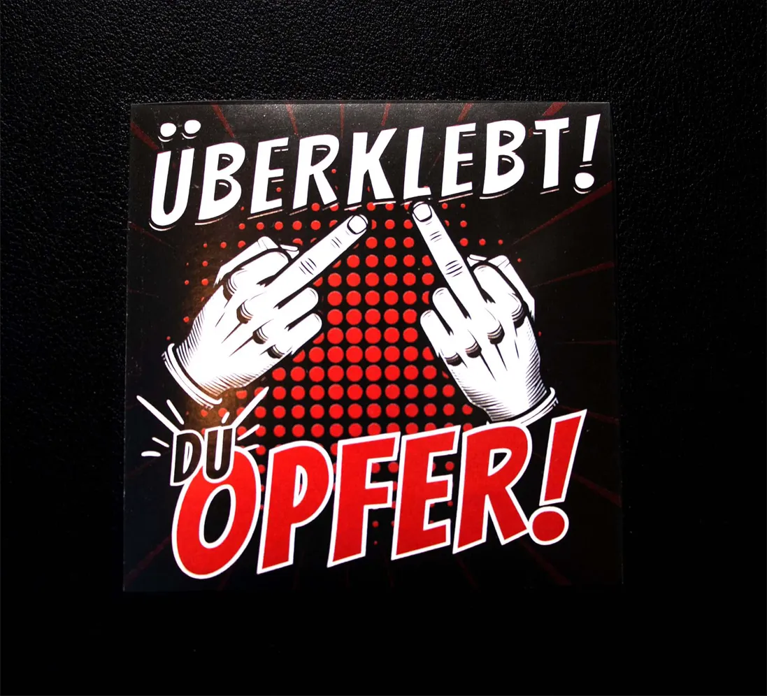 Sticker mit Aufschrift überklebt du opfer und Comic-Mittelfinger auf schwarzem Hintergrund mit rotem Pop-Art-Stil